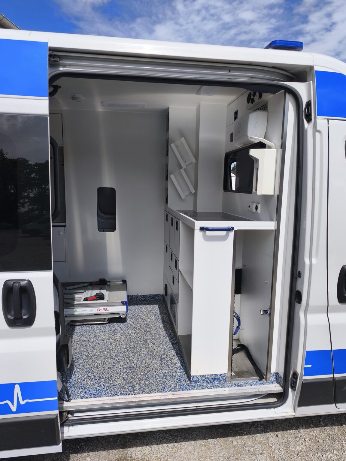 Porte latérale ouverte de l'ambulance ASSU et sa cellule sanitaire aménagée